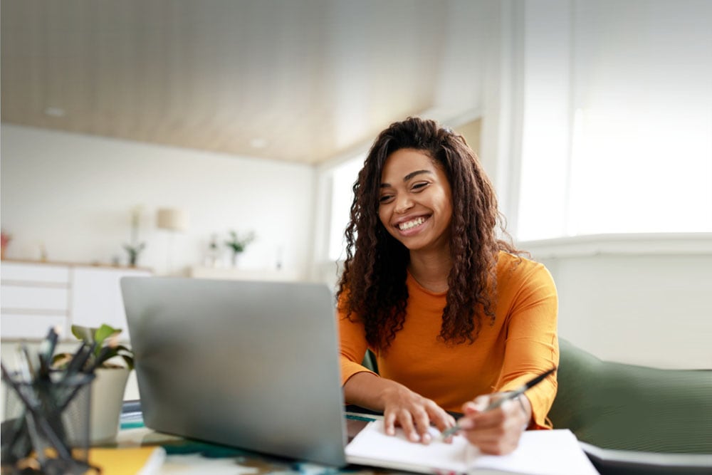 Online school student in Louisiana on her laptop and writing in a notebook