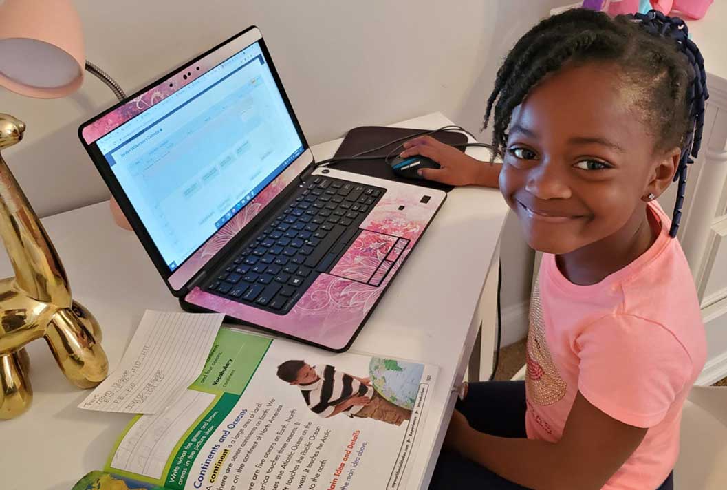Young student in a pink shirt smiling during their online studies at TEC Connections Academy